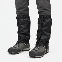 Black ripstop gaiters with front closure and elastic top and bottom, worn over grey hiking shoes on a white background. 9
