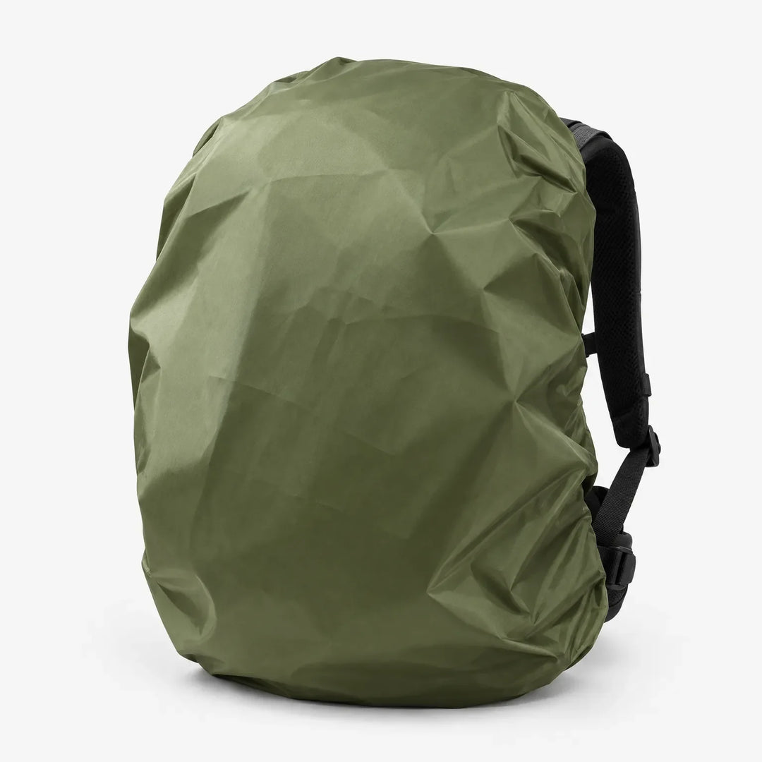 Olive green rucksack cover fitted over a backpack, seen at an angle with the black shoulder straps and buckles visible. 5