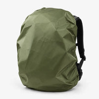 Olive green rucksack cover fitted over a backpack, seen at an angle with the black shoulder straps and buckles visible. 5