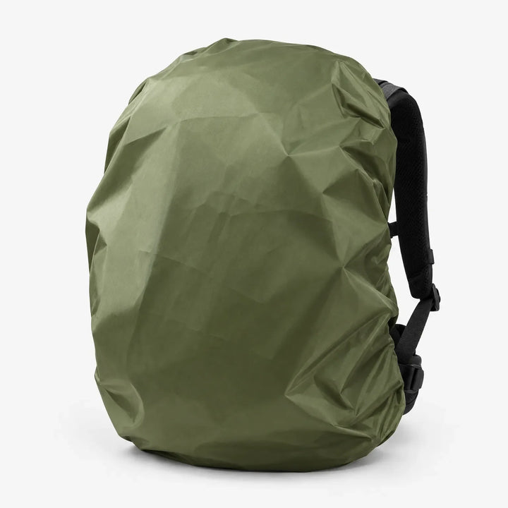 Olive green rucksack cover fitted over a backpack, seen at an angle with the black shoulder straps and buckles visible. 5