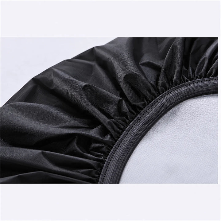 Close-up detail of the black cover's elasticated hem, gathered fabric and woven edging, over a pale grey surface. 6