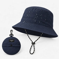 Navy bucket hat with water droplets on the crown, shown beside its small round packable pouch with clip. 5