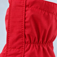 Extreme close-up of the red ripstop fabric, showing the stitched seam beside the zip panel and the gathered elastic section. 6