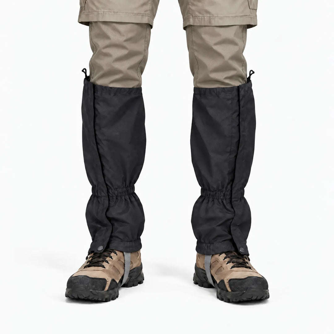 Front view of black gaiters worn over hiking boots with beige trousers, showing the front closure flap, snap fasteners and elastic cuffs. 9