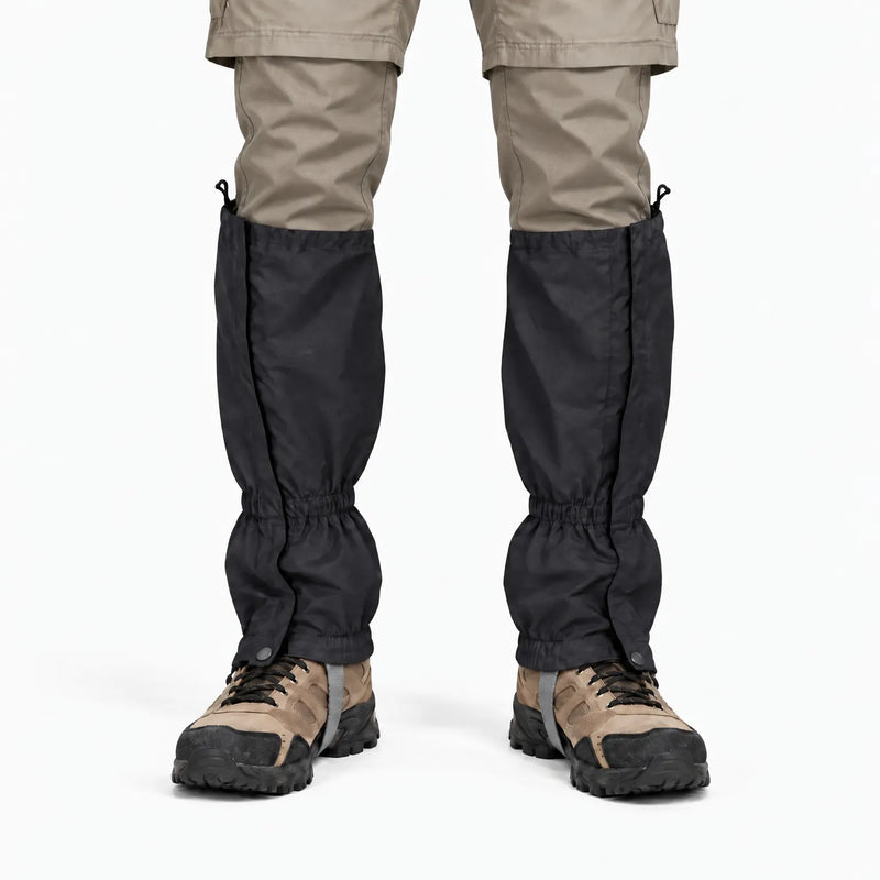 Front view of black gaiters worn over hiking boots with beige trousers, showing the front closure flap, snap fasteners and elastic cuffs. 9