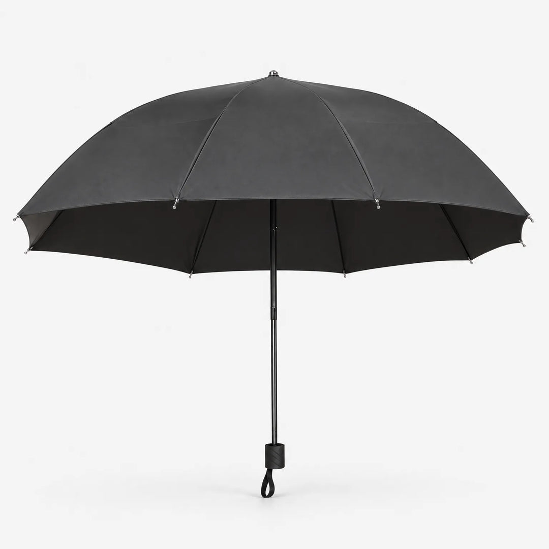 Open dark grey umbrella seen from the side on white, showing its wide canopy, black lining and handle with wrist loop. 3