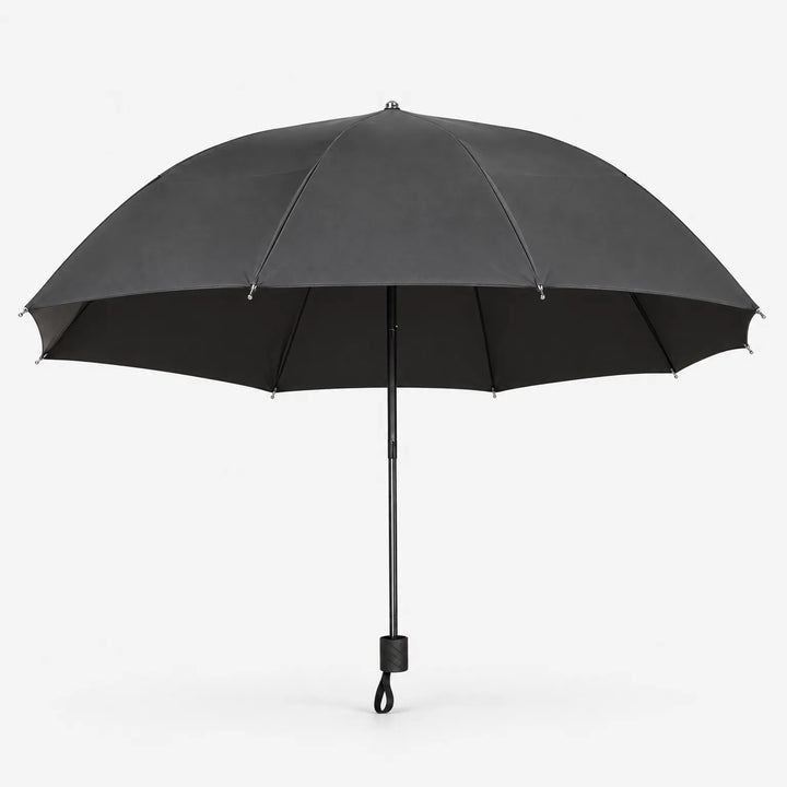 Open dark grey umbrella seen from the side on white, showing its wide canopy, black lining and handle with wrist loop. 3