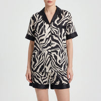 Front view of a model wearing the short-sleeved version of the zebra-print pyjamas with matching shorts and black trim. 5