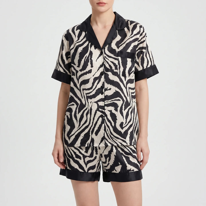 Front view of a model wearing the short-sleeved version of the zebra-print pyjamas with matching shorts and black trim. 5