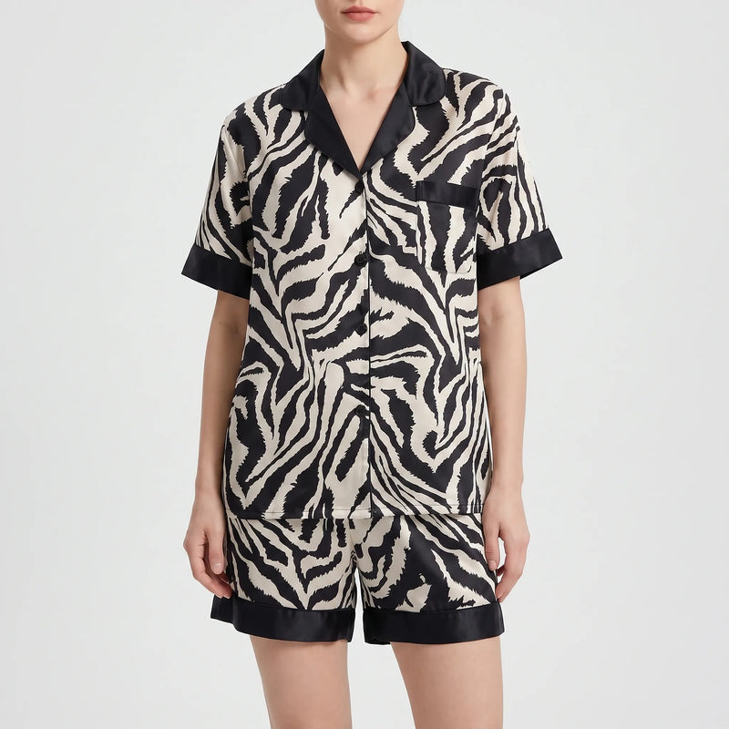Front view of a model wearing the short-sleeved version of the zebra-print pyjamas with matching shorts and black trim. 5