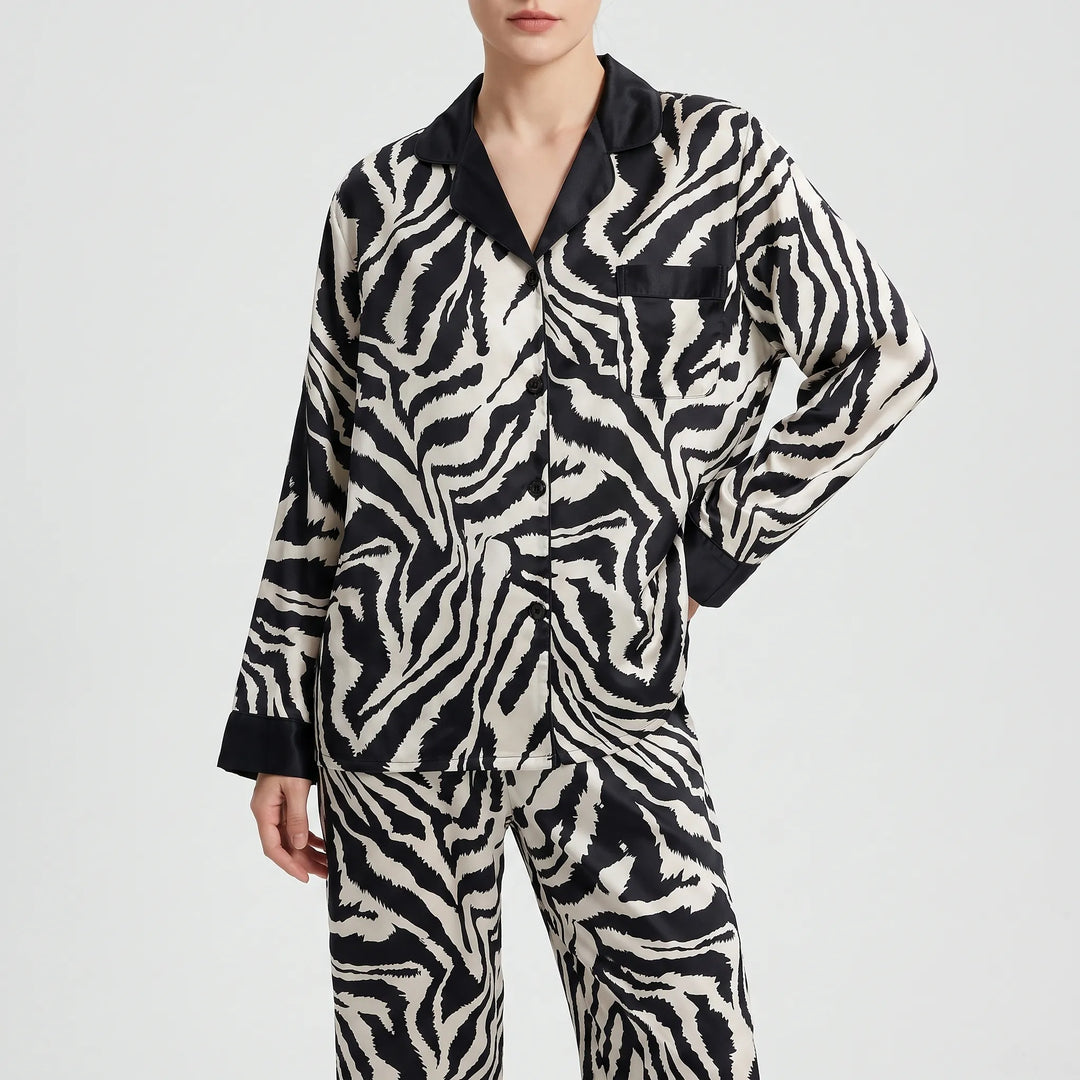 Front view of a model in the long-sleeved zebra-print pyjama shirt with black collar, buttons and pocket, worn with matching trousers. 6