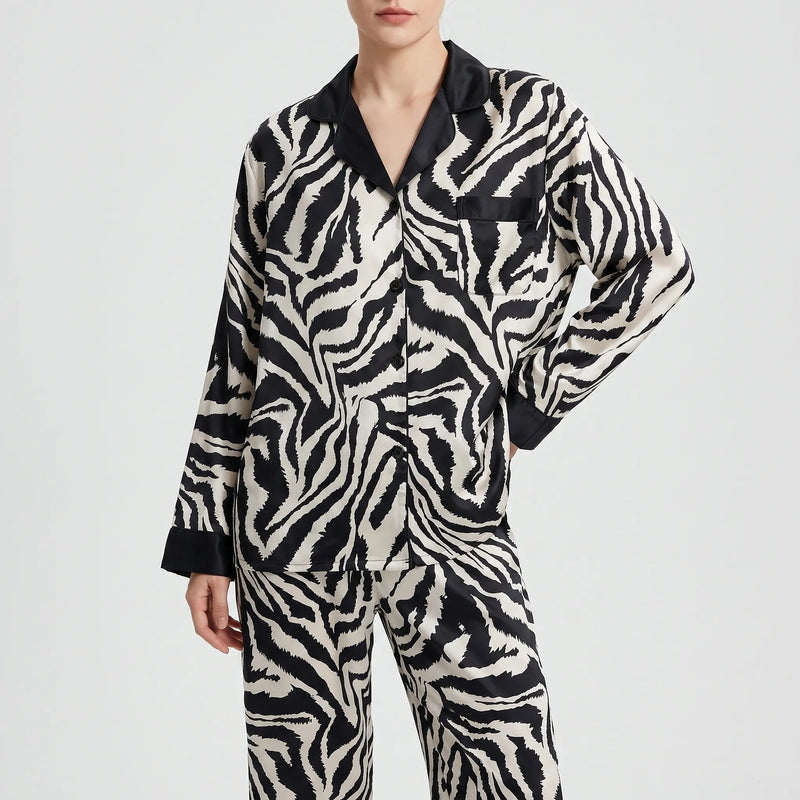 Front view of a model in the long-sleeved zebra-print pyjama shirt with black collar, buttons and pocket, worn with matching trousers. 6