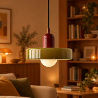 Glossy olive pendant with red cap, lit warmly, in front of a bookshelf 60