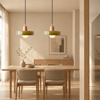 Two olive glass pendants with coral caps hang above a wooden dining table in a bright room 1