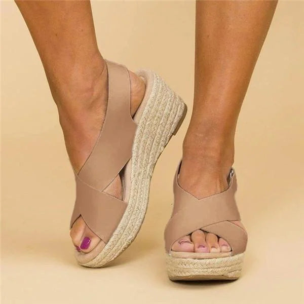 Front view of beige crossover-strap wedge sandals with open toes and jute-wrapped soles, worn by a model 3