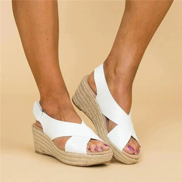 White crossed-strap wedge sandals with woven jute soles and open toes, worn and seen at an angle 6
