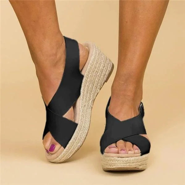 Front three-quarter view of black crossover wedge espadrilles with open toes and a woven jute wedge 8