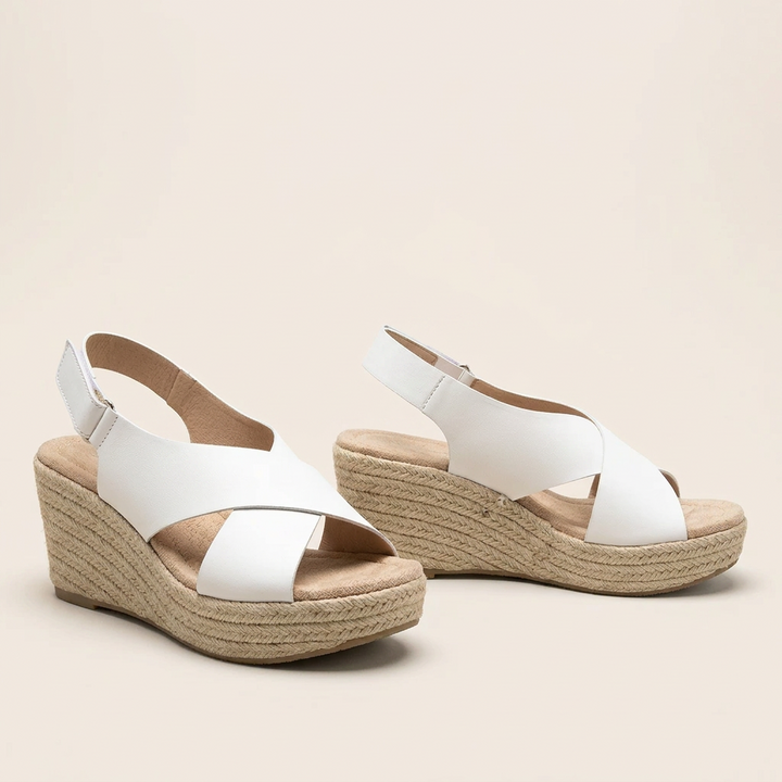 Pair of white crossover wedge sandals with padded footbeds and braided jute wedges against a cream background 15