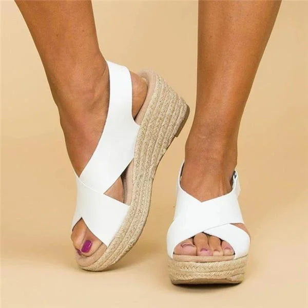 Front three-quarter view of white crossover-strap espadrille wedges on feet, showing the open toe and woven jute edge 11