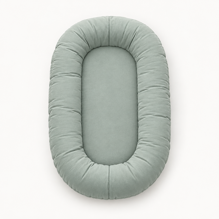 Empty sage-green oval lounger with a plump padded rim, seen from above 8