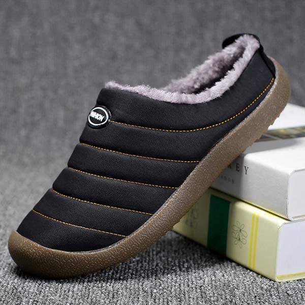 Single black slipper propped on books, showing the quilted upper and brown rubber sole 10