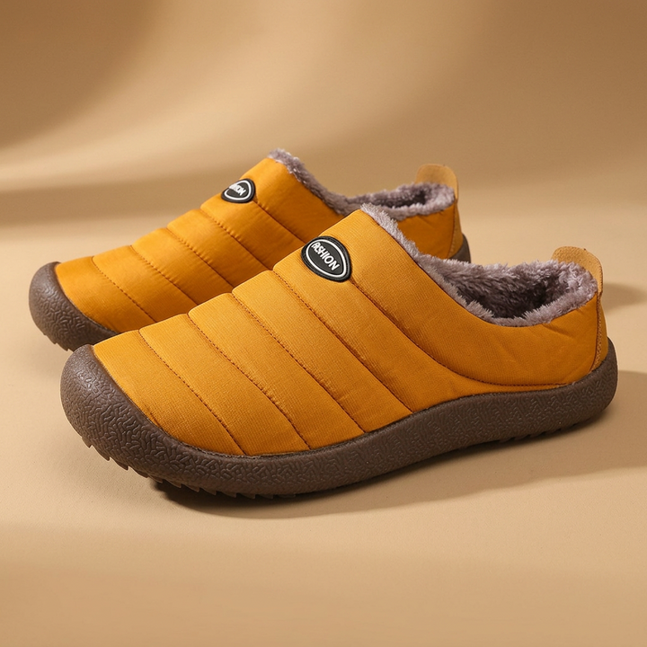 Pair of mustard yellow quilted slippers with brown fleece lining and dark brown soles on beige 20