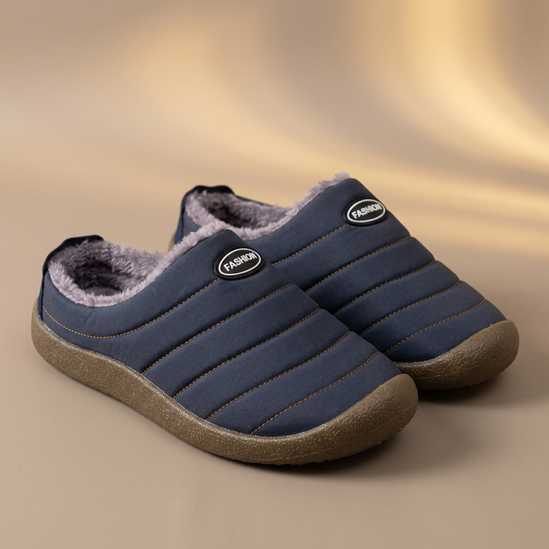 Pair of navy blue quilted slippers with soft grey lining on a warm beige studio backdrop 18