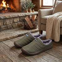 Olive green quilted fleece-lined slippers on a wooden floor by a lit stone fireplace 1