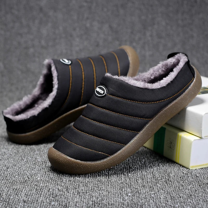 Black slippers with orange stitching and soft fleece collar, one tilted against books on carpet 9