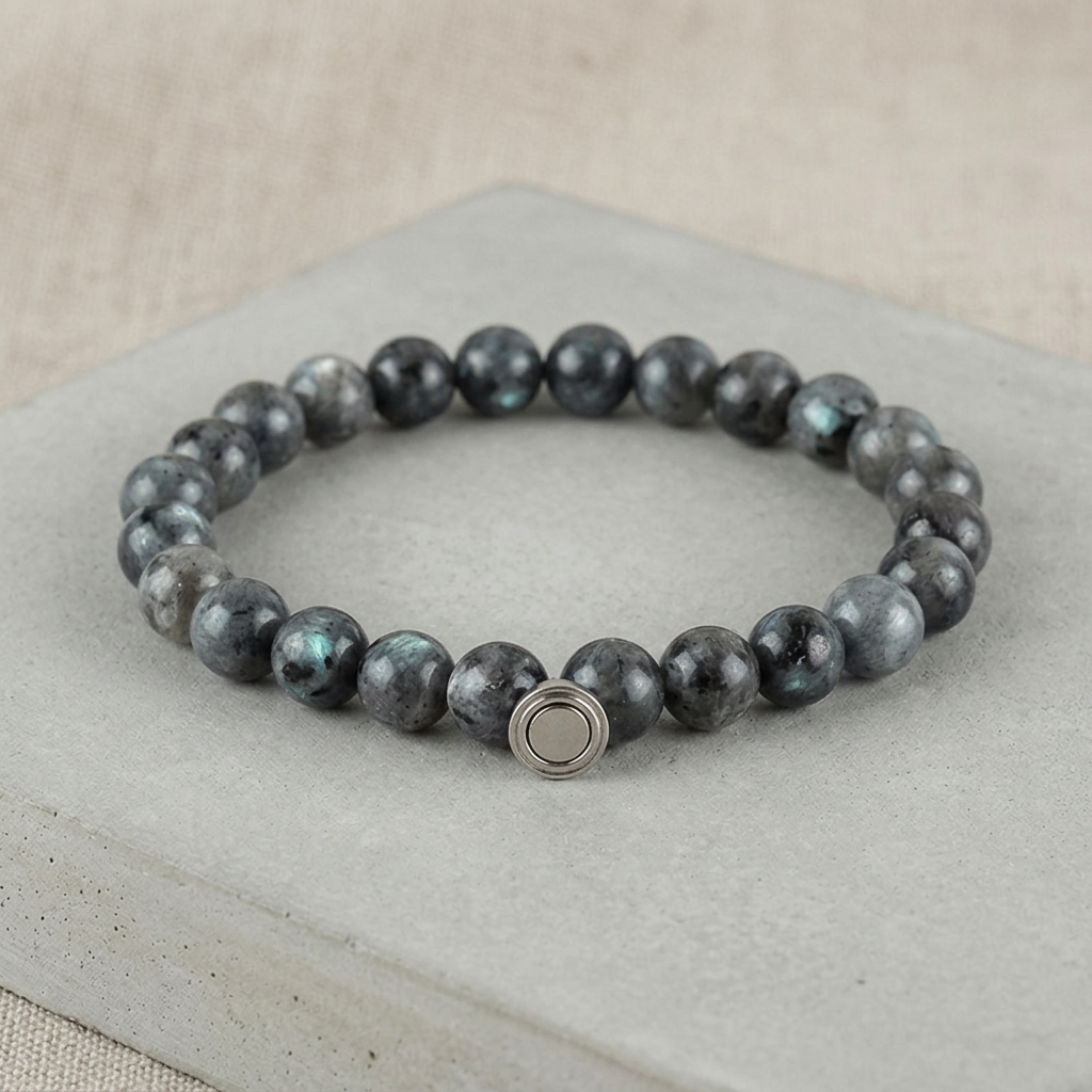 Dark grey bead bracelet with hints of blue-green shimmer and silver clasp on a grey concrete slab 4