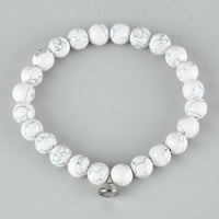 Flat lay of a bracelet of white round beads with grey veining and a silver clasp 3