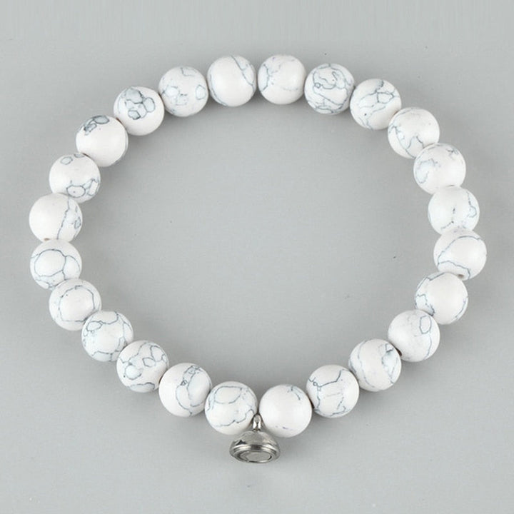 Flat lay of a bracelet of white round beads with grey veining and a silver clasp 3