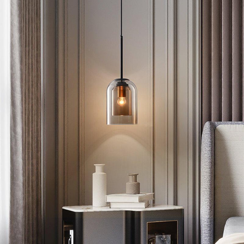 Single amber-toned pendant glowing above a marble-topped bedside table with vases, books and a grey headboard 3