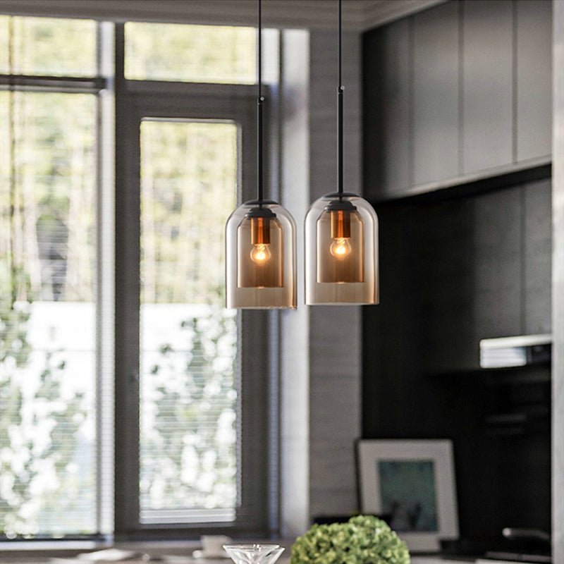 Pair of amber pendants hanging in a kitchen beside a tall window 4