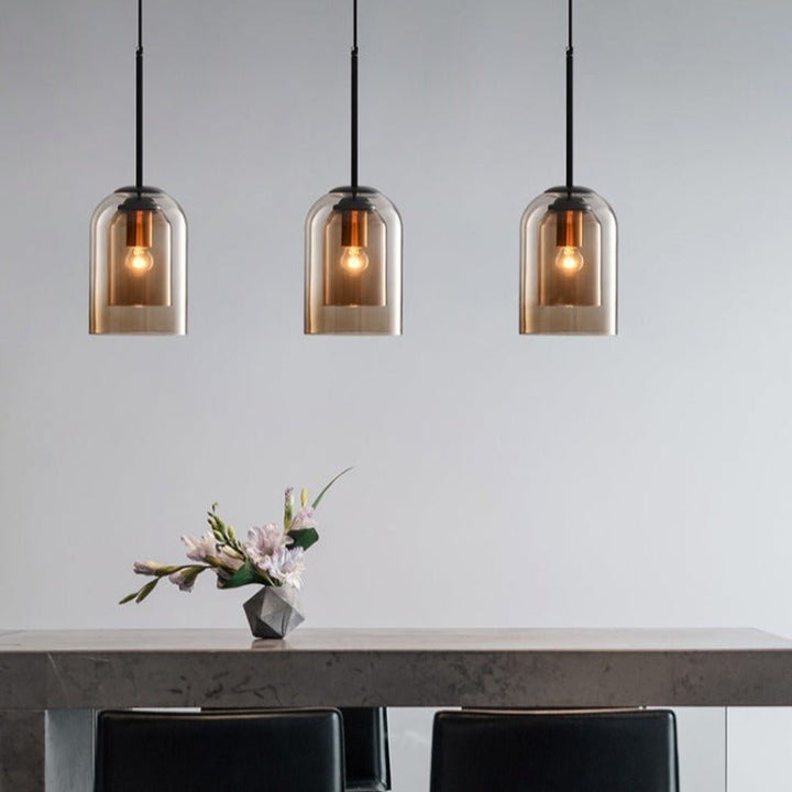 Three amber pendants in a row over a stone dining table with flowers and black chairs 6