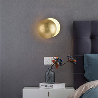 Smooth gold lamp on a grey wall above a bedside table with a vase of berries 7