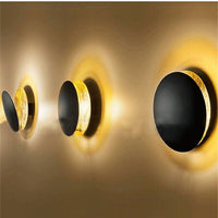 Row of three lamps with black front discs and gold edges, seen from the side 10