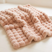 Pale pink blanket with large round fluffy bubbles, laid out with a gentle fold on a white floor 15