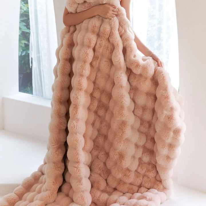 Blush pink bubble-textured throw held against the body, draping in long fluffy folds to the floor 4