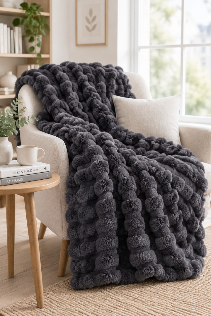 Dark grey bubble-textured blanket draped over a cream armchair beside a wooden side table 14