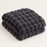 Dark grey bubble-textured plush blanket folded in a stack on a plain light background 14
