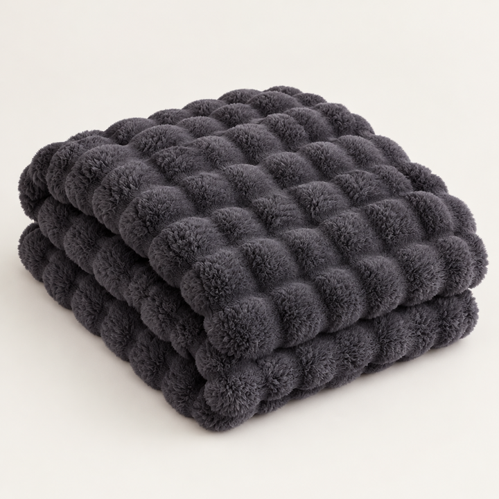 Dark grey bubble-textured plush blanket folded in a stack on a plain light background 14