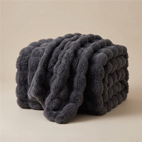 Dark grey plush bubble-textured blanket folded and draped against a neutral studio backdrop 14