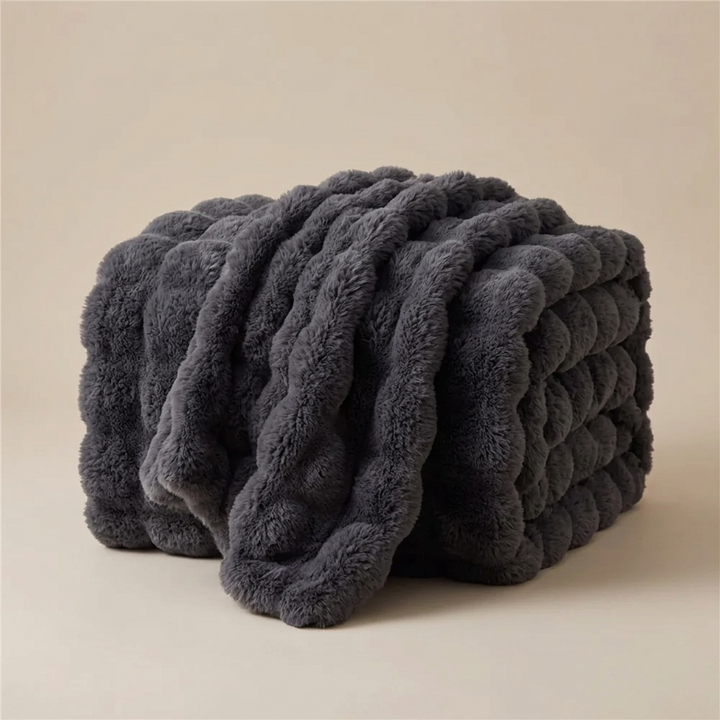 Dark grey plush bubble-textured blanket folded and draped against a neutral studio backdrop 14