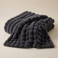 Dark grey fluffy blanket with a raised bubble texture, draped in soft folds on a plain background 14