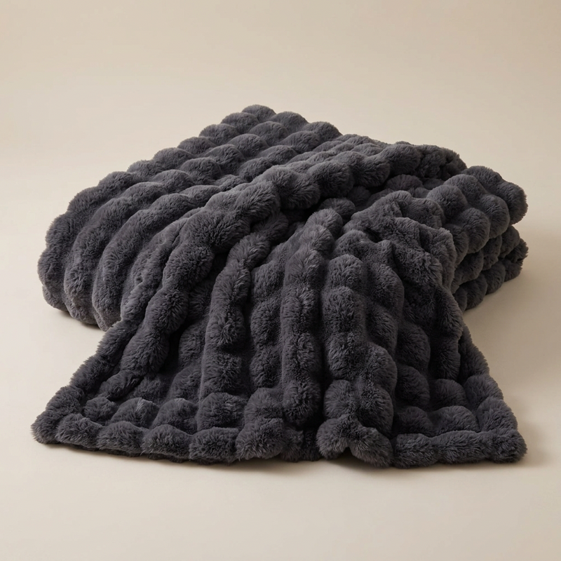 Dark grey fluffy blanket with a raised bubble texture, draped in soft folds on a plain background 14