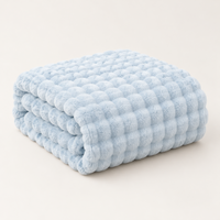 Pale blue plush blanket folded in a neat stack on a plain light background 12