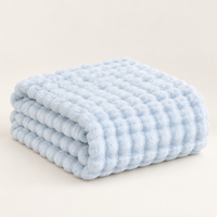 Light blue plush blanket folded in a stack with fine, soft bubble texture on a light background 17