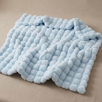 Light blue fluffy bubble-textured blanket lying slightly rumpled on a beige surface 17