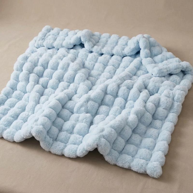 Light blue fluffy bubble-textured blanket lying slightly rumpled on a beige surface 17